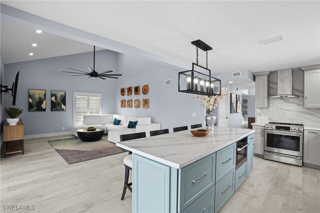 kitchen with backsplash, wall chimney range hood, a kitchen breakfast bar, stainless steel electric range, and light wood-style floors