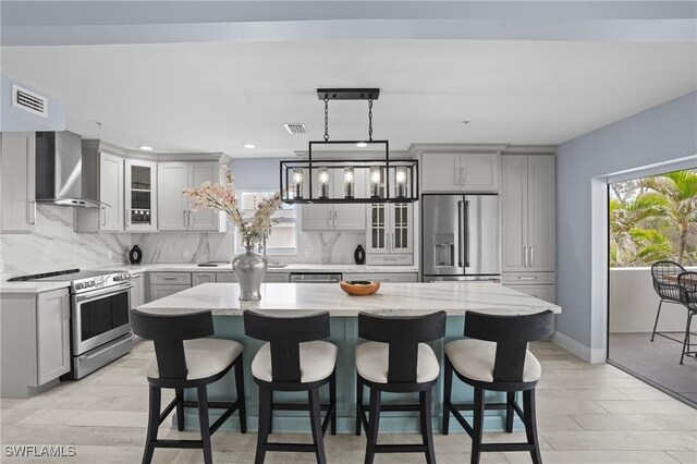 kitchen featuring visible vents, backsplash, a wealth of natural light, appliances with stainless steel finishes, and wall chimney exhaust hood