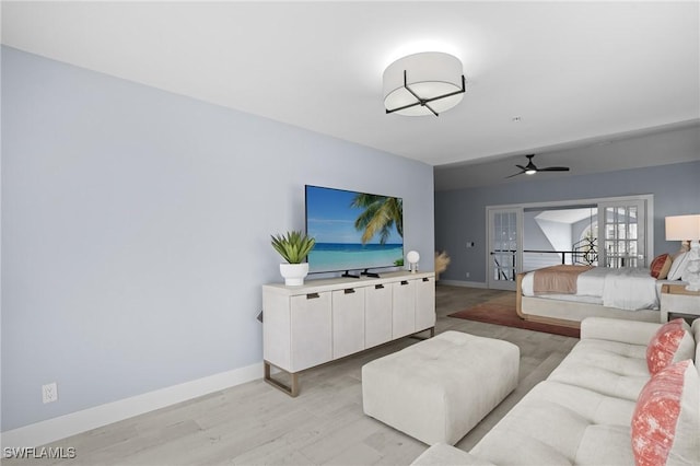 living room featuring a ceiling fan, light wood-style floors, and baseboards