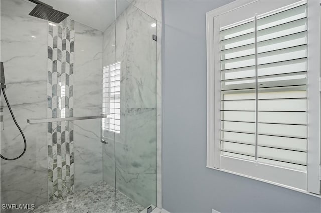 bathroom with a marble finish shower and plenty of natural light