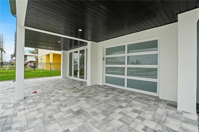 view of patio featuring french doors, an attached garage, and fence