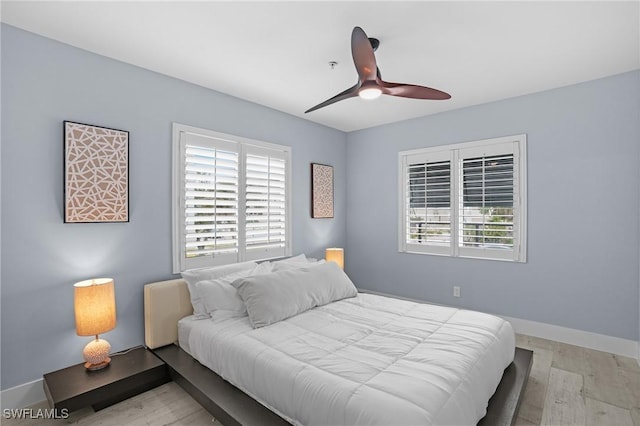 bedroom with light wood-type flooring, baseboards, and a ceiling fan