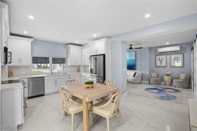 kitchen featuring white cabinetry, stainless steel appliances, light countertops, and a wall unit AC