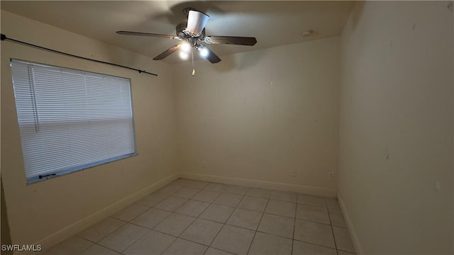 empty room with light tile patterned floors, ceiling fan, and baseboards