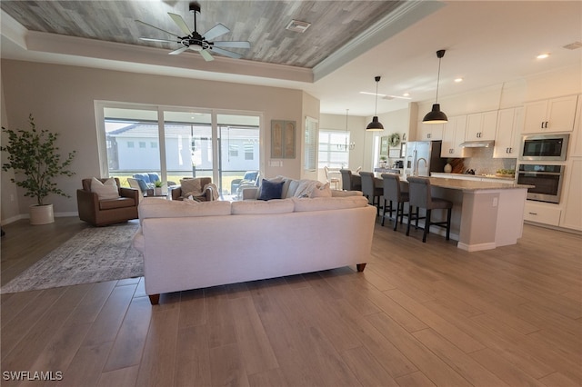 living area featuring visible vents, baseboards, dark wood finished floors, crown molding, and a raised ceiling