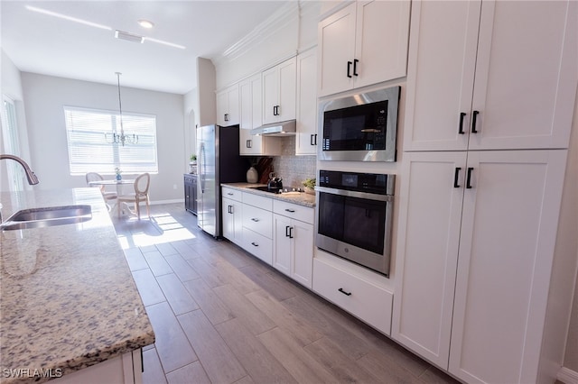 kitchen featuring visible vents, backsplash, wood finish floors, stainless steel appliances, and a sink