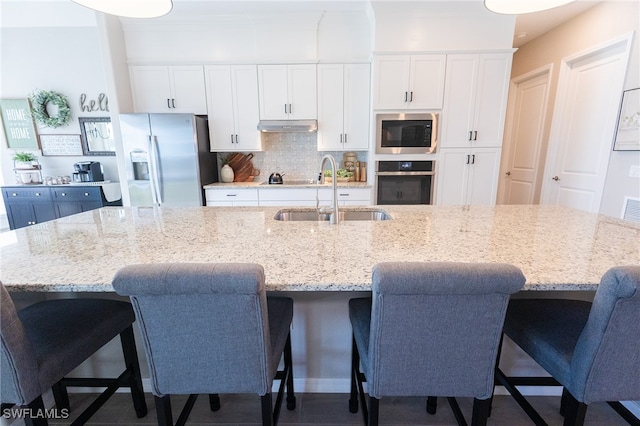 kitchen featuring decorative backsplash, white cabinets, stainless steel appliances, and a sink