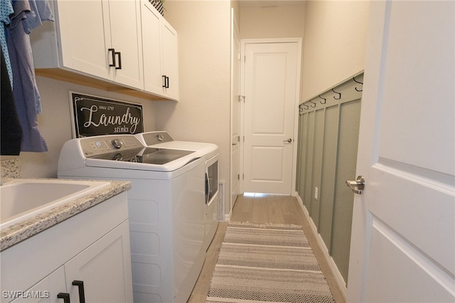 washroom with washer and dryer, cabinet space, and light wood-type flooring