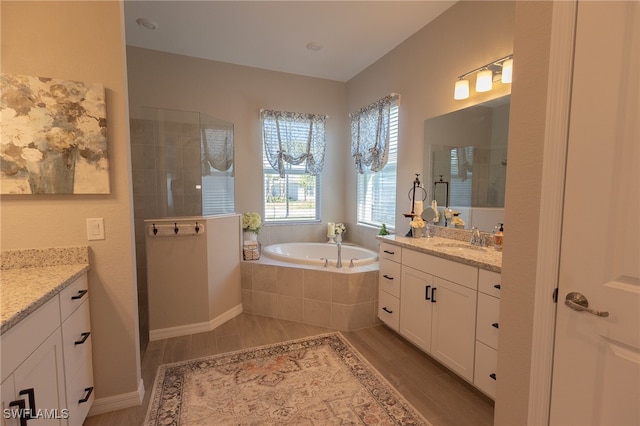 bathroom featuring a garden tub, vanity, walk in shower, and wood finished floors