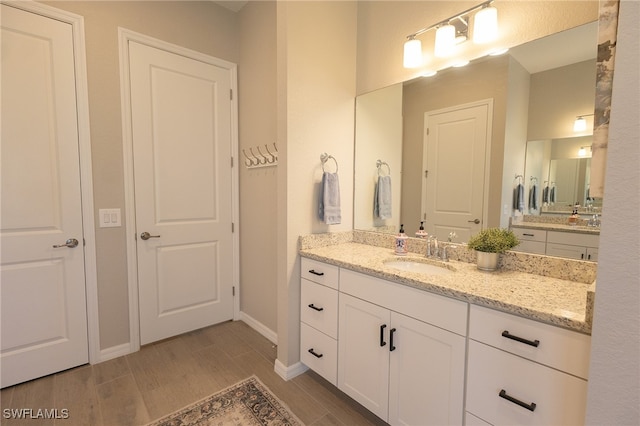 full bath with vanity, baseboards, and wood finished floors