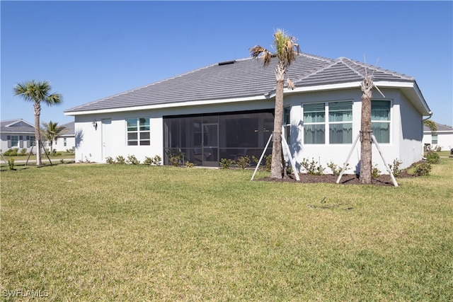 rear view of property featuring a yard, a sunroom, and stucco siding