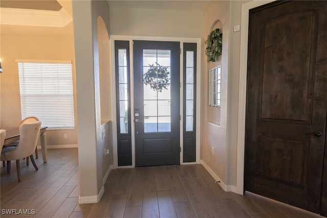 foyer entrance with ornamental molding, baseboards, and wood finished floors