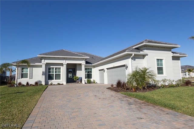 prairie-style house with stucco siding, a front lawn, decorative driveway, and a garage