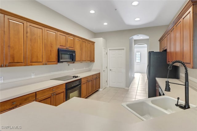 17498 Old Harmony Dr Unit 202, Fort Myers, FL 33908 - kitchen with light tile patterned floors, recessed lighting, arched walkways, brown cabinetry, and black appliances