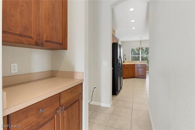 17498 Old Harmony Dr Unit 202, Fort Myers, FL 33908 - kitchen with baseboards, light countertops, light tile patterned floors, black refrigerator with ice dispenser, and brown cabinetry