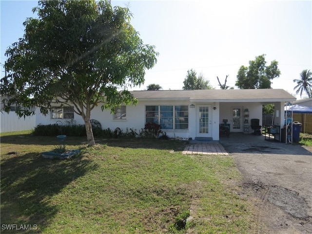 ranch-style house with an attached carport, driveway, a front lawn, and stucco siding