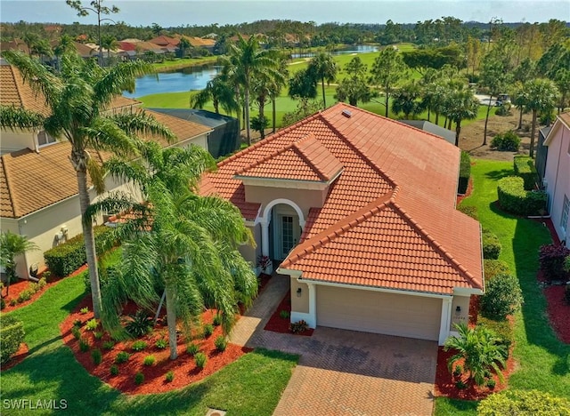 view of front of property with a water view, a tile roof, stucco siding, decorative driveway, and a garage