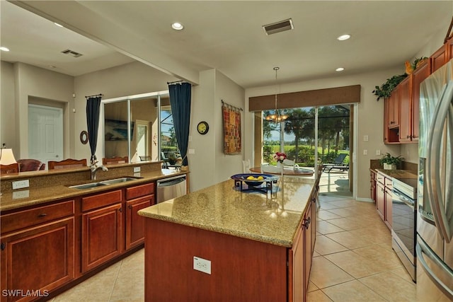 kitchen with visible vents, a kitchen island, light stone counters, stainless steel appliances, and a sink