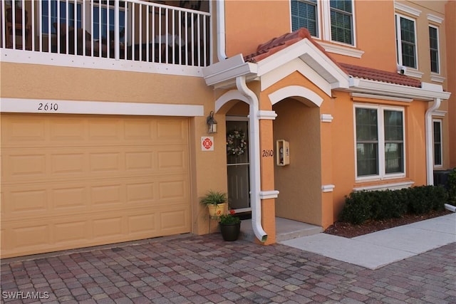 property entrance featuring a garage and stucco siding