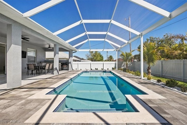 view of pool with a ceiling fan, a patio, glass enclosure, and a fenced backyard