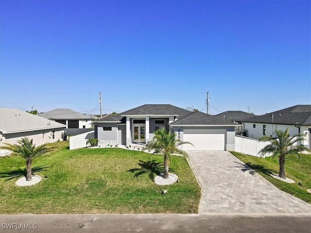 prairie-style home featuring stucco siding, a front lawn, decorative driveway, fence, and an attached garage