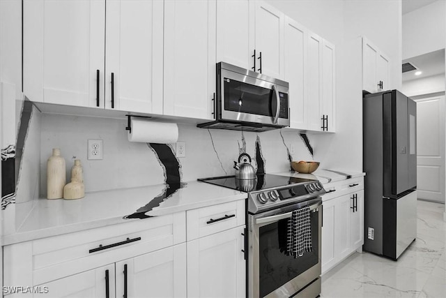 kitchen with marble finish floor, appliances with stainless steel finishes, white cabinetry, and light countertops