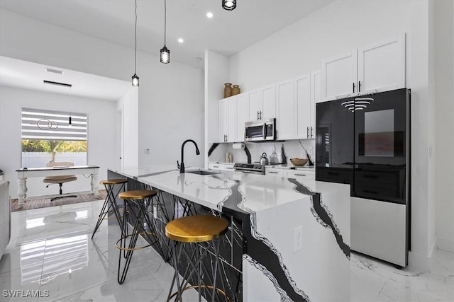 kitchen with marble finish floor, appliances with stainless steel finishes, white cabinets, and a sink