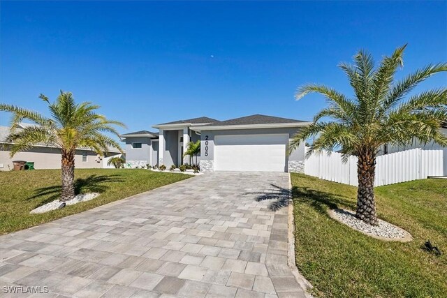 prairie-style home with stucco siding, a front lawn, decorative driveway, fence, and an attached garage