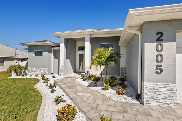 view of exterior entry featuring stucco siding and stone siding