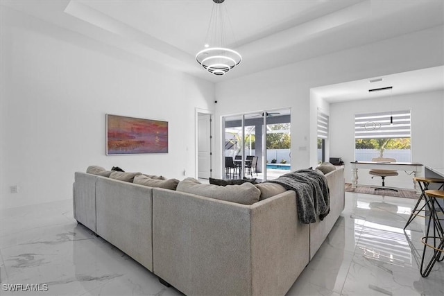 living room featuring a tray ceiling, plenty of natural light, and marble finish floor