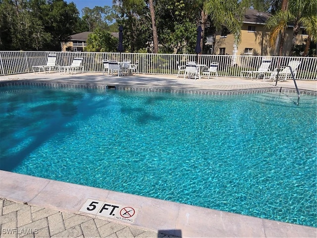 community pool with a patio area and fence