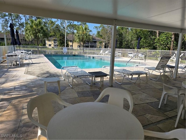 pool with outdoor dining space, a patio, and fence