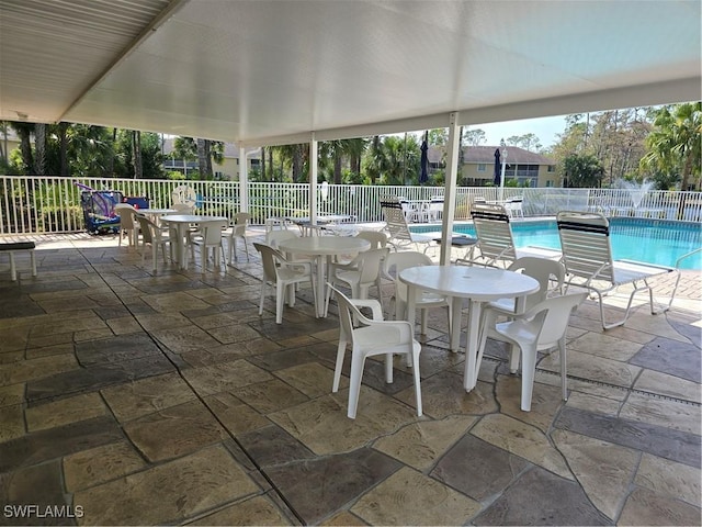 view of patio with outdoor dining area, a community pool, and fence