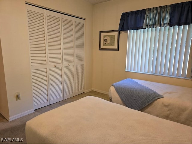 carpeted bedroom with a closet and baseboards