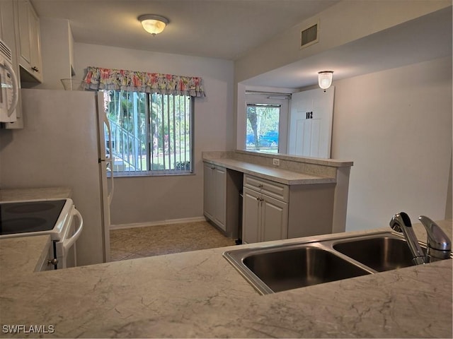 kitchen featuring visible vents, a sink, white electric range oven, baseboards, and light stone countertops