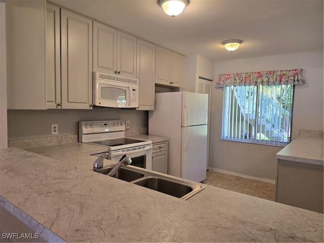 kitchen with a sink, white appliances, white cabinetry, and light countertops