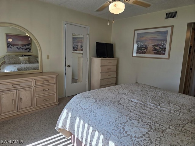 bedroom with a textured ceiling, carpet, visible vents, and ceiling fan