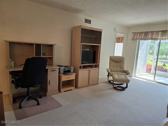 office area featuring visible vents, carpet floors, and a textured ceiling