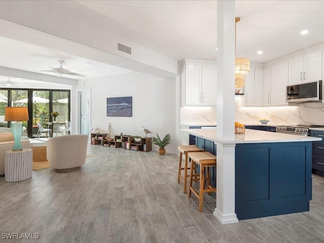 kitchen featuring visible vents, light countertops, white cabinets, appliances with stainless steel finishes, and backsplash