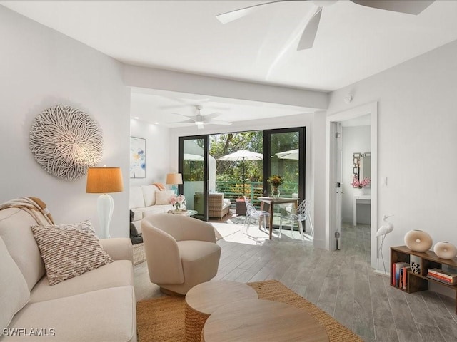 living area with baseboards, ceiling fan, and wood finished floors