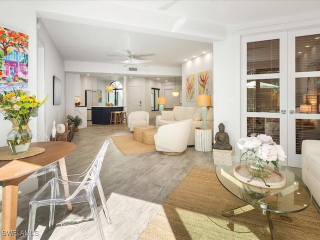 living room featuring visible vents, a ceiling fan, and light wood-type flooring