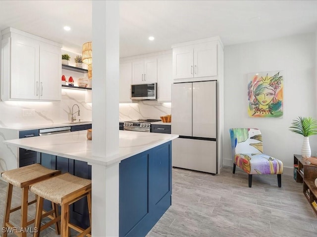 kitchen with a sink, appliances with stainless steel finishes, white cabinetry, and open shelves