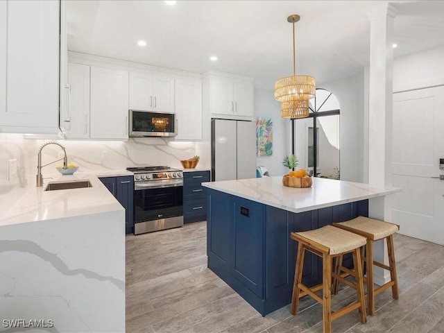 kitchen featuring a sink, appliances with stainless steel finishes, white cabinetry, blue cabinets, and backsplash