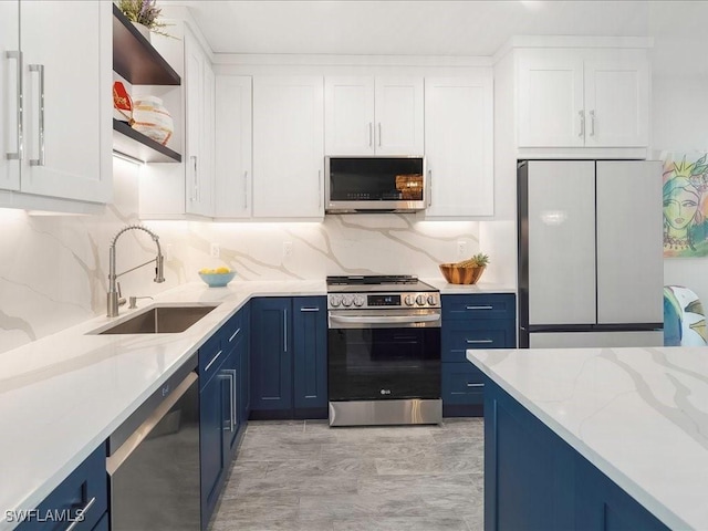 kitchen with open shelves, blue cabinetry, a sink, appliances with stainless steel finishes, and white cabinetry