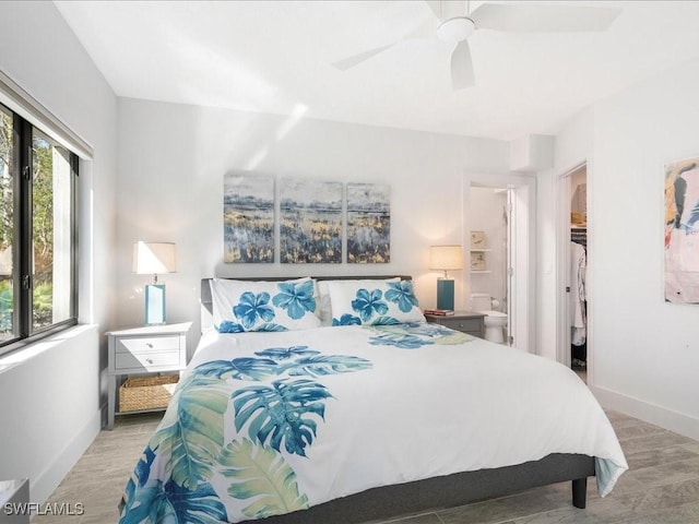 bedroom with ceiling fan, a walk in closet, baseboards, and wood finished floors