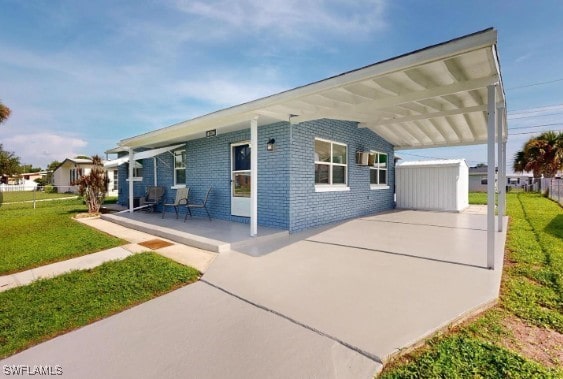 exterior space featuring a front yard, fence, a carport, and brick siding