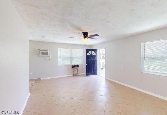 foyer featuring ceiling fan, an AC wall unit, and baseboards