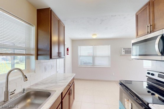 kitchen featuring decorative backsplash, brown cabinetry, appliances with stainless steel finishes, and a sink