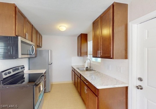 kitchen with brown cabinets, a sink, tasteful backsplash, stainless steel appliances, and light countertops