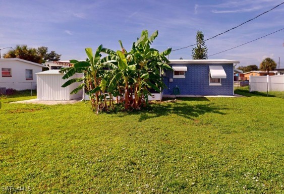 rear view of house with brick siding, a yard, and fence